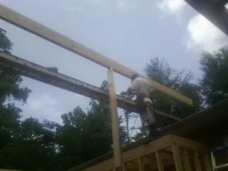 Carpenter setting a ridge beam over a new addition frame — Ice Dam Removal by Roofing Brothers in Flowery Branch