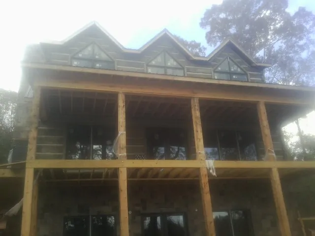 Dormers and porch framing on a large log home under construction — Roof Coating work by our crew in Flowery Branch