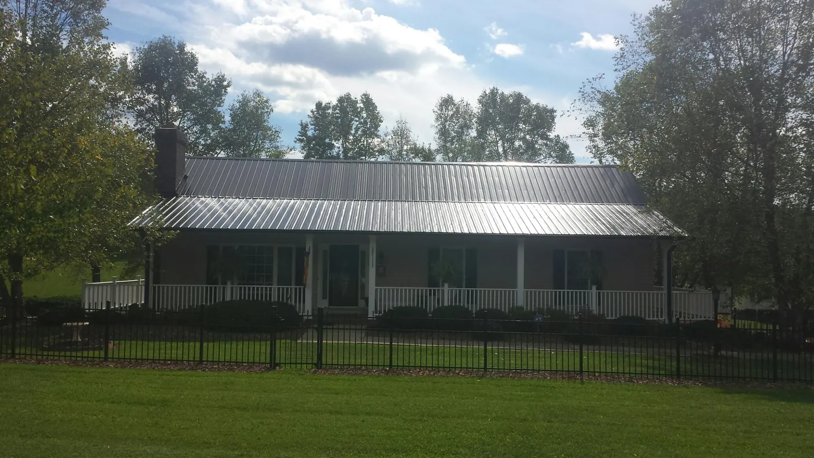 Gray metal roof on a brick ranch with a full width front porch — Gutter Guard Installation work by our crew in Flowery Branch