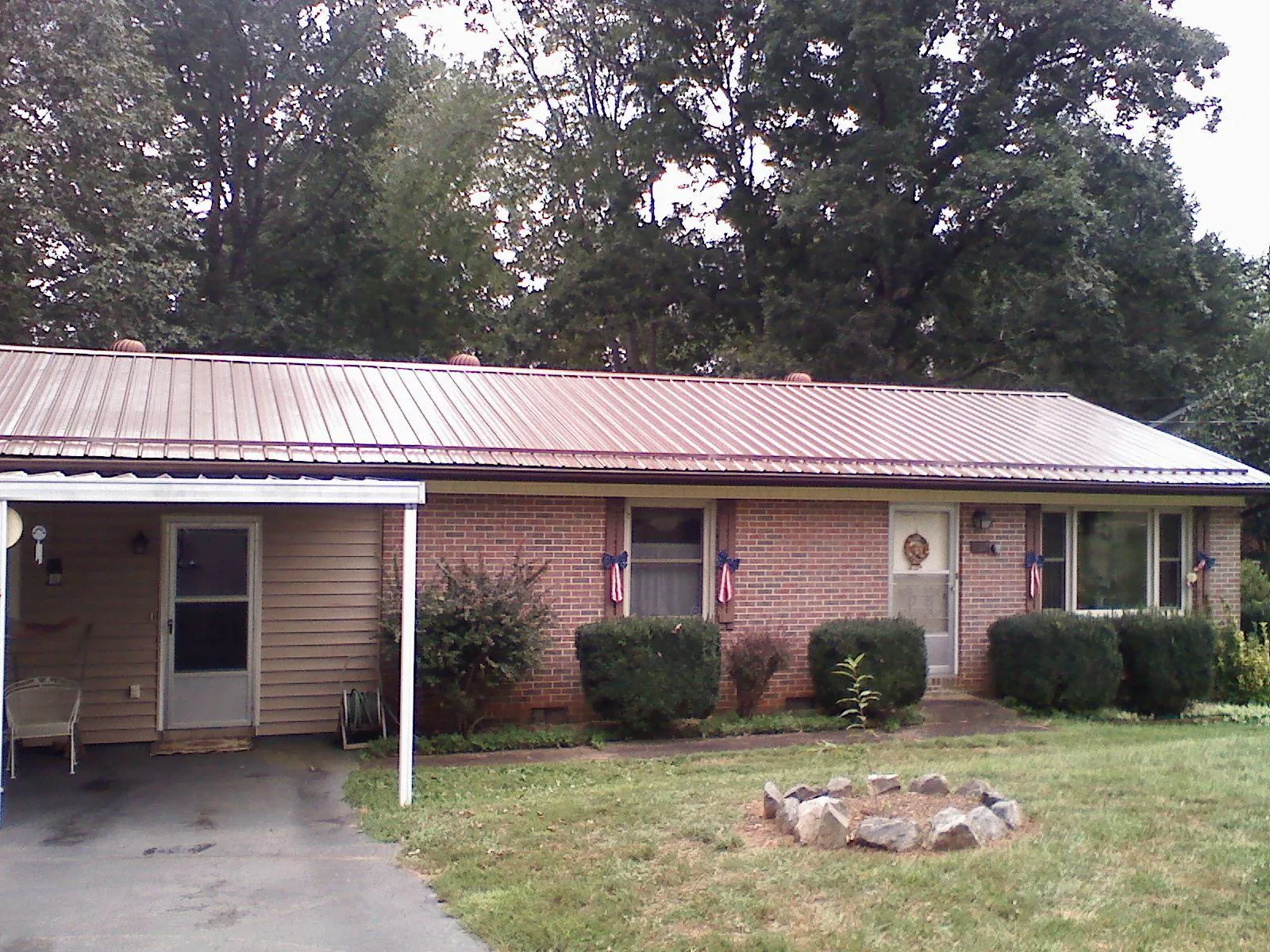 Bronze metal roof and carport on a brick ranch home — Roof Repair work by our crew in Flowery Branch