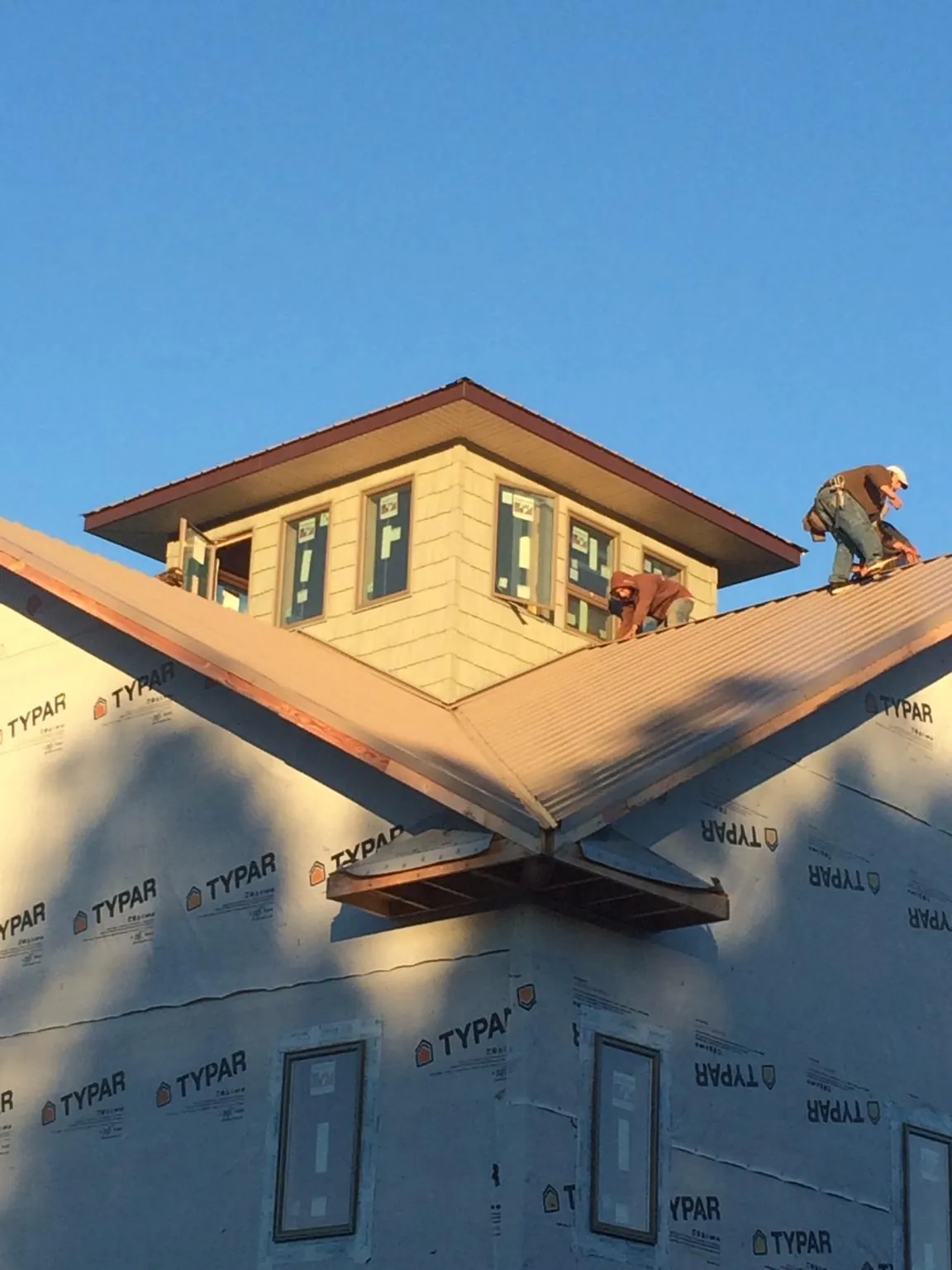 Roofers working around a rooftop cupola on a new metal roof at sunset — Roof Waterproofing in Flowery Branch by Roofing Brothers